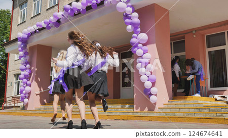 Happy students celebrating the end of the school year by running out of the school building after their last class 124674641