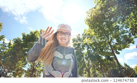 Beautiful twelve-year-old teenager girl posing and spinning in front of a video camera on the background of the summer sunshine. Beautiful twelve-year-old teenager girl posing and spinning in front of a video camera on the background of the summer sunshine. 124674730