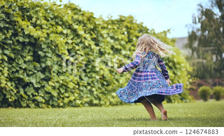 Barefoot girl twirling in a garden, her dress swirling around her, enjoying a carefree summer day outdoors Barefoot girl twirling in a garden, her dress swirling around her, enjoying a carefree summer day outdoors 124674883