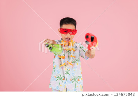 Songkran festival cheer as a happy boy in a floral shirt and glasses holds two water gun 124675048