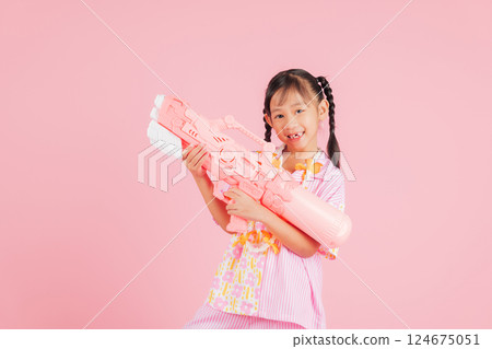 Songkran fun with a happy girl in a floral shirt holding a toy water gun Songkran fun with a happy girl in a floral shirt holding a toy water gun 124675051