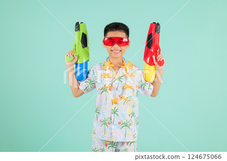 Songkran fun moments with a joyful boy in glasses and a floral shirt holding two toy water pistols 124675066