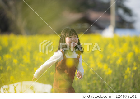A spring moment with a smiling girl surrounded by rape blossoms 124675101