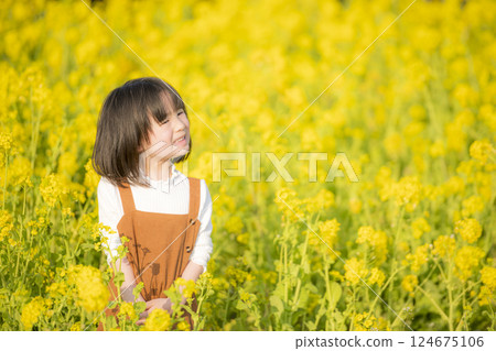 A spring moment with a smiling girl surrounded by rape blossoms 124675106