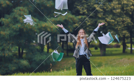 Jubilant student tossing papers skyward, marking academic year's conclusion with exuberant celebration in sunlit park Jubilant student tossing papers skyward, marking academic year's conclusion with exuberant celebration in sunlit park 124675223