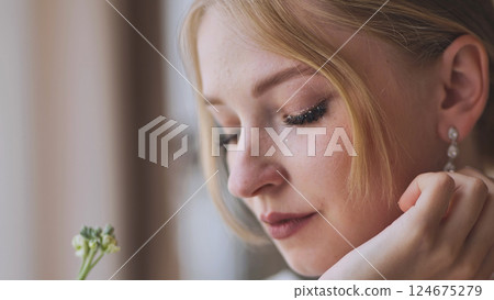 Glittery bride leaning hand on chin, exuding serene happiness during wedding day preparations with soft, contemplative expression Glittery bride leaning hand on chin, exuding serene happiness during wedding day preparations with soft, contemplative expression 124675279