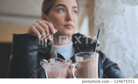 Woman relaxing at cafe, sipping milkshake, enjoying ice cream during quiet afternoon break 124675551