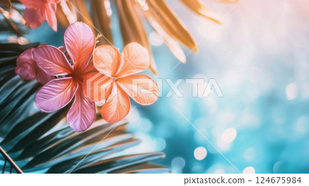 vibrant tropical flowers and palm leaves glowing softly in the sunlight with a dreamy blue bokeh background 124675984