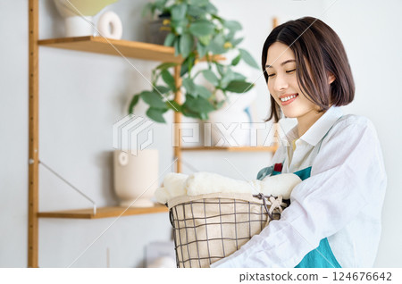 Young woman holding a laundry basket Young woman holding a laundry basket 124676642