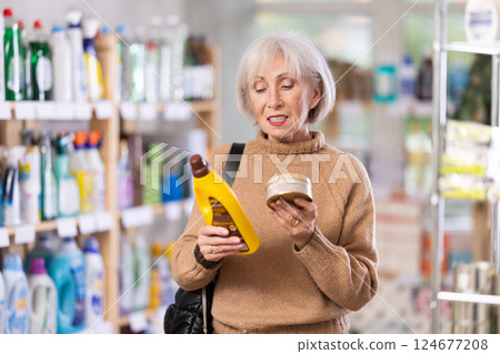 Elderly housewife buys a cleaning product for washing parquet and laminate floors in supermarket 124677208