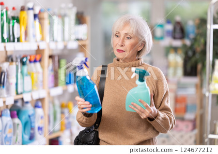 Mature woman choosing cleaning spray in department store 124677212