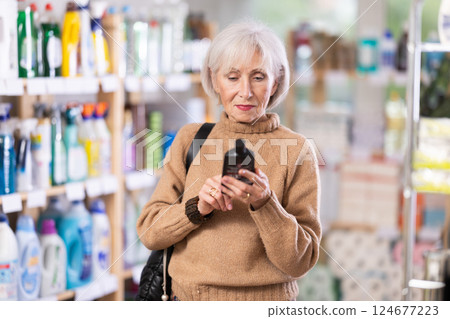 Mature woman chooses products for glass-ceramics Mature woman chooses products for glass-ceramics 124677223