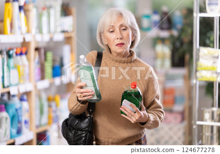 Mature woman choosing dishwashing detergents Mature woman choosing dishwashing detergents 124677278