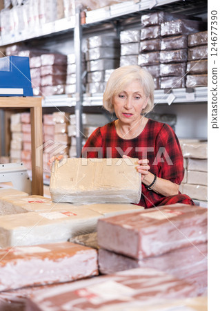 Elderly woman chooses pottery clay in shop Elderly woman chooses pottery clay in shop 124677390