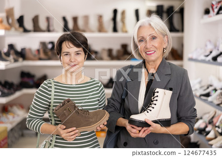 Adult and elderly women choosing boots in store 124677435