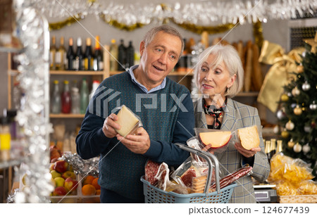 Elderly couple is looking at cheese in store on eve of New Year holidays Elderly couple is looking at cheese in store on eve of New Year holidays 124677439