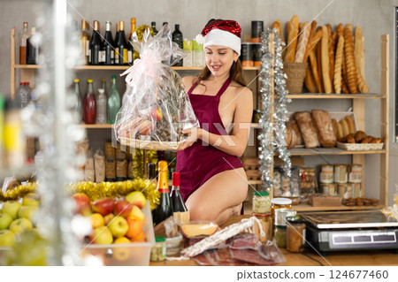 Young woman in apron and santa hat with gift box of food 124677460