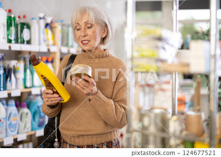 Elderly housewife buys a cleaning product for washing parquet and laminate floors in supermarket Elderly housewife buys a cleaning product for washing parquet and laminate floors in supermarket 124677521