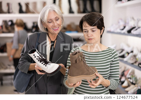 Adult and elderly women choosing boots in store Adult and elderly women choosing boots in store 124677524