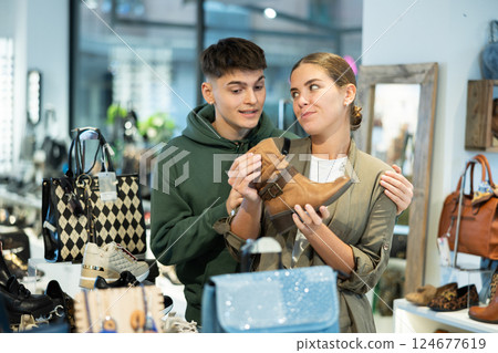 Guy male friend strongly recommends his young woman colleague to pay attention to model of boots Guy male friend strongly recommends his young woman colleague to pay attention to model of boots 124677619