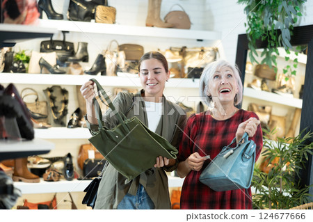 Elderly woman with young girl friend inspects shop window and is looking for modern handbag 124677666