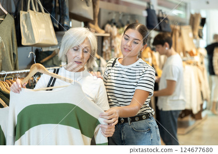 Two women choosing convenient jumper in clothing store Two women choosing convenient jumper in clothing store 124677680