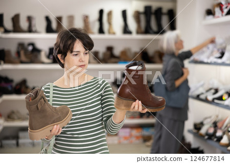 Woman takes samples from showcase and examines shoes 124677814