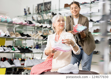 Elderly woman and young woman trying on sneakers in shoe store Elderly woman and young woman trying on sneakers in shoe store 124677830