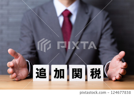 Additional tariff block and middle-aged male businessman in a suit Additional tariff block and middle-aged male businessman in a suit 124677838