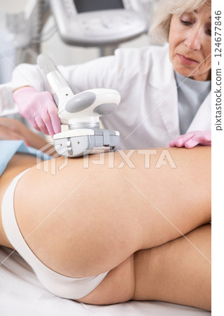 Old woman specialist doing LPG massage of hips of young woman 124677846