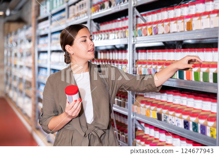 Young woman chooses bottles of paint in shop 124677943