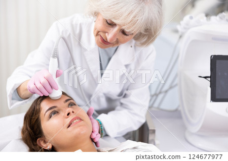 Young woman having face laser therapy procedure by specialist 124677977
