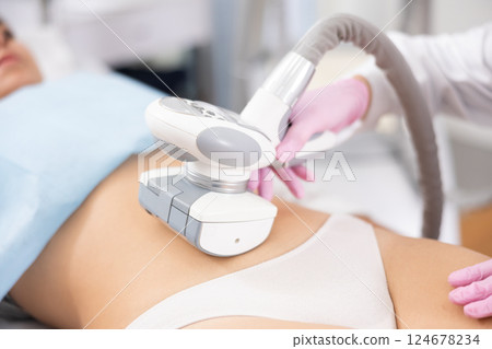 LPG massage device applied on young woman's belly 124678234