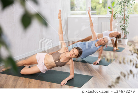 Young woman standing in balancing side plank pose Vasisthasana Young woman standing in balancing side plank pose Vasisthasana 124678279