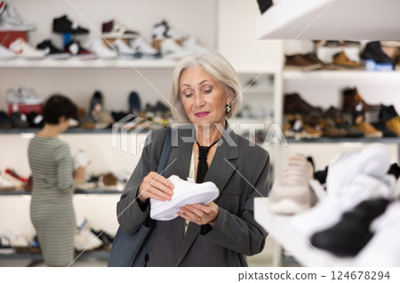 Senior woman takes samples from showcase and examines snickers Senior woman takes samples from showcase and examines snickers 124678294