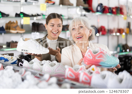 Elderly woman and young woman choosing sneakers in shoe store Elderly woman and young woman choosing sneakers in shoe store 124678307