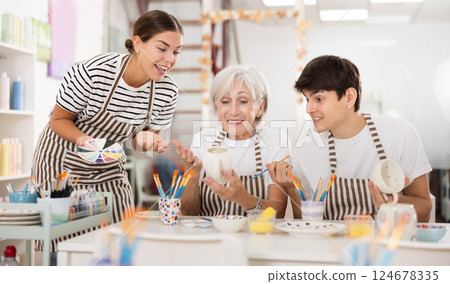 Group of cheerful people painting ceramic dishware in pottery class Group of cheerful people painting ceramic dishware in pottery class 124678335
