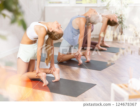 Teenage girl performing asana Ustrasana during group yoga training Teenage girl performing asana Ustrasana during group yoga training 124678367