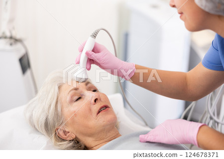 Old woman having face laser therapy procedure 124678371
