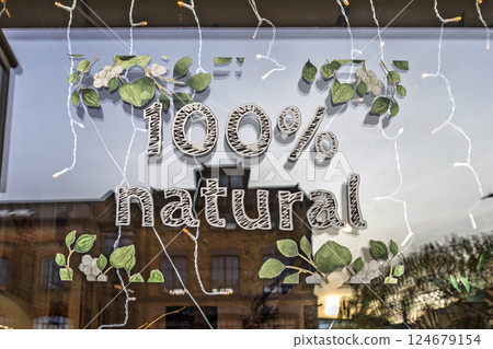 100 Percent natural window sign with leaves and warm lighting in shopfront display 124679154