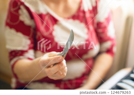 A skilled woman with a sharp knife in a wellequipped kitchen, ready to prepare a delicious meal A skilled woman with a sharp knife in a wellequipped kitchen, ready to prepare a delicious meal 124679263