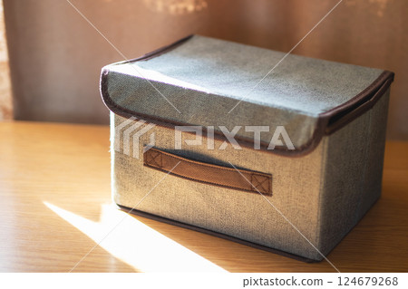 A shiny silver box featuring a brown handle sits atop a wooden table A shiny silver box featuring a brown handle sits atop a wooden table 124679268