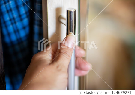 A close up view of a person s hand firmly gripping a door handle A close up view of a person s hand firmly gripping a door handle 124679271