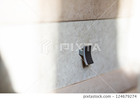 There is a black knob mounted on a wall that has a white background 124679274