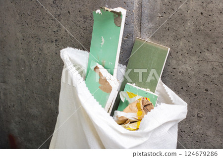 A white bag that is filled with various green and white pieces of paper 124679286
