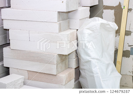 There is a stack of white bricks located next to a white bag There is a stack of white bricks located next to a white bag 124679287