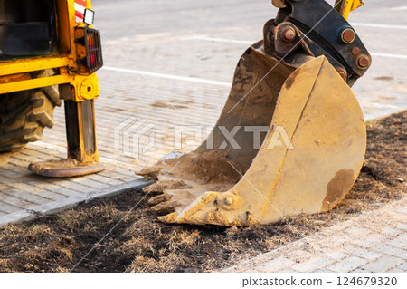 A construction bulldozer is actively digging a substantial hole in the ground A construction bulldozer is actively digging a substantial hole in the ground 124679320