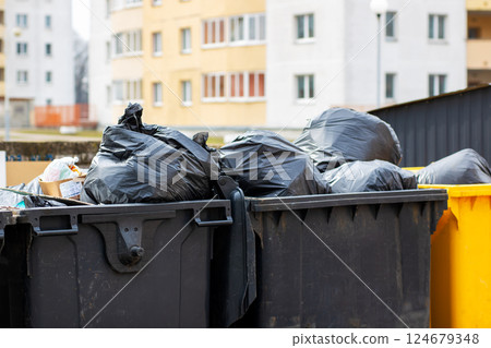 Trash cans filled with garbage in front of a building 124679348