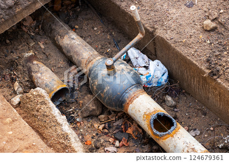 A pipe that has a hole in it is currently laying in the dirt A pipe that has a hole in it is currently laying in the dirt 124679361