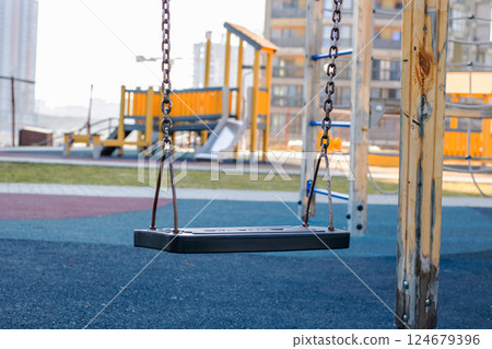 An Empty Swing at a Modern Playground is All Set and Ready for Lots of Fun and Enjoyment An Empty Swing at a Modern Playground is All Set and Ready for Lots of Fun and Enjoyment 124679396